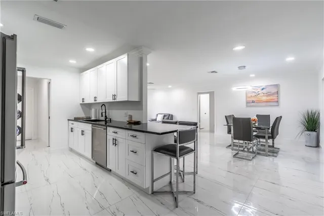 a kitchen with stainless steel appliances granite countertop a table chairs sink and cabinets