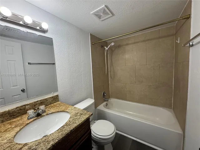 a bathroom with a granite countertop sink mirror toilet and bathtub