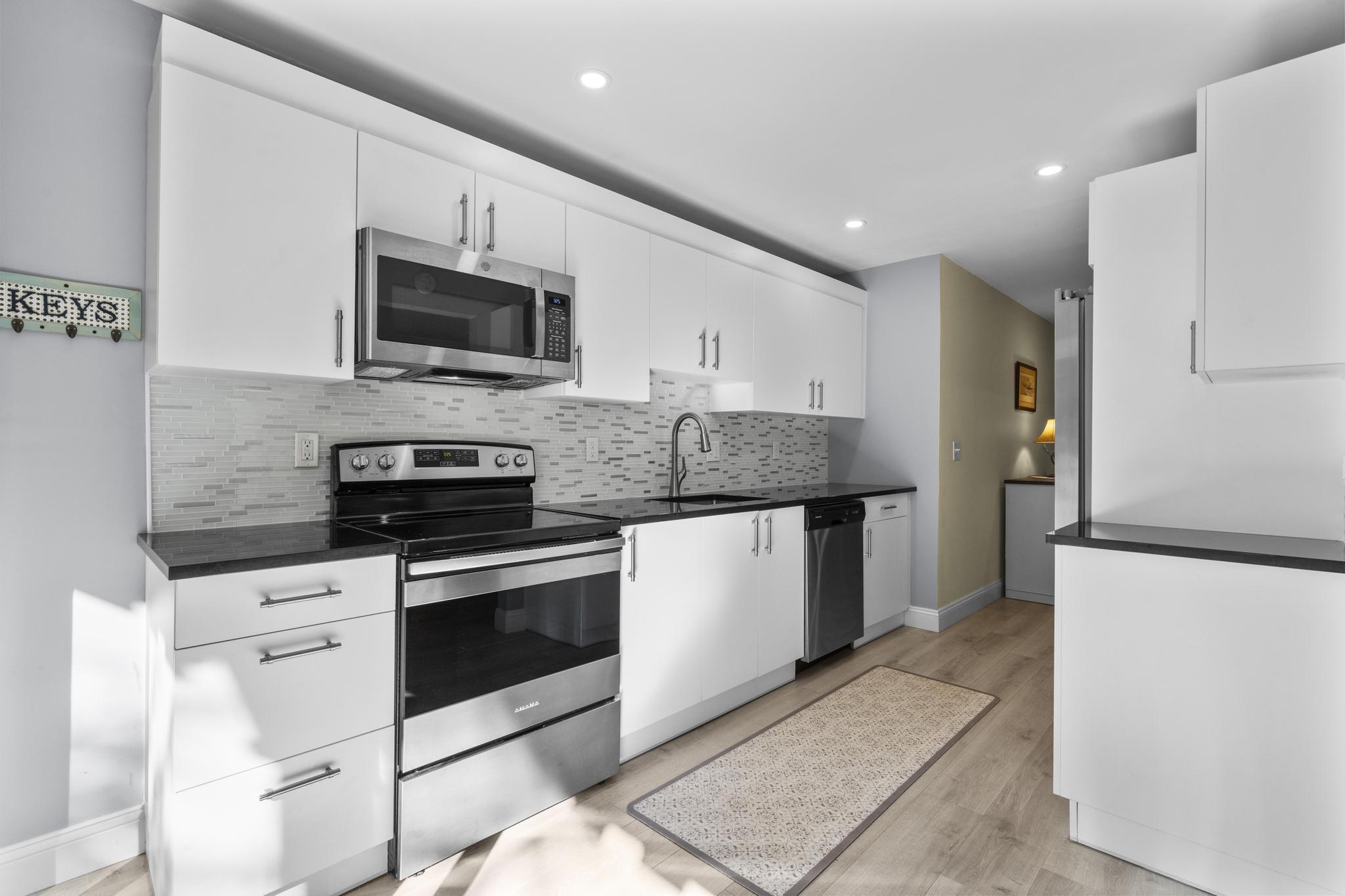 28 Mill Hill Road, Unit 28 Fairfield, CT 06890 - Photo 16 of 37 a kitchen with stainless steel appliances kitchen island granite countertop a stove a sink and a microwave