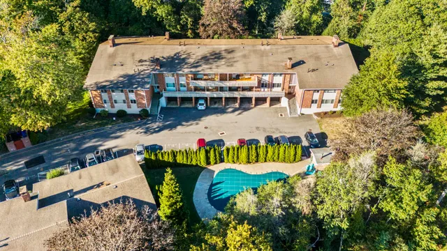 an aerial view of a house with swimming pool and large trees
