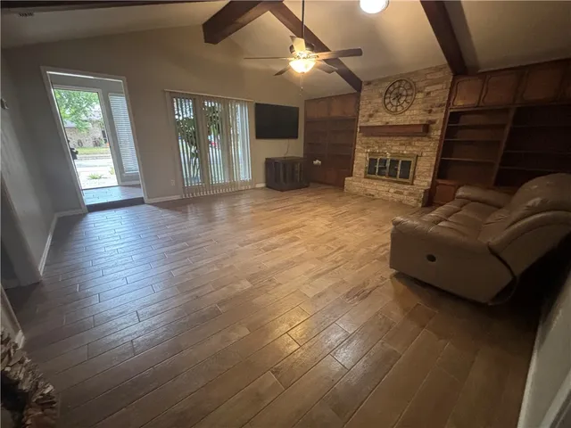 an empty room with wooden floor fan and window
