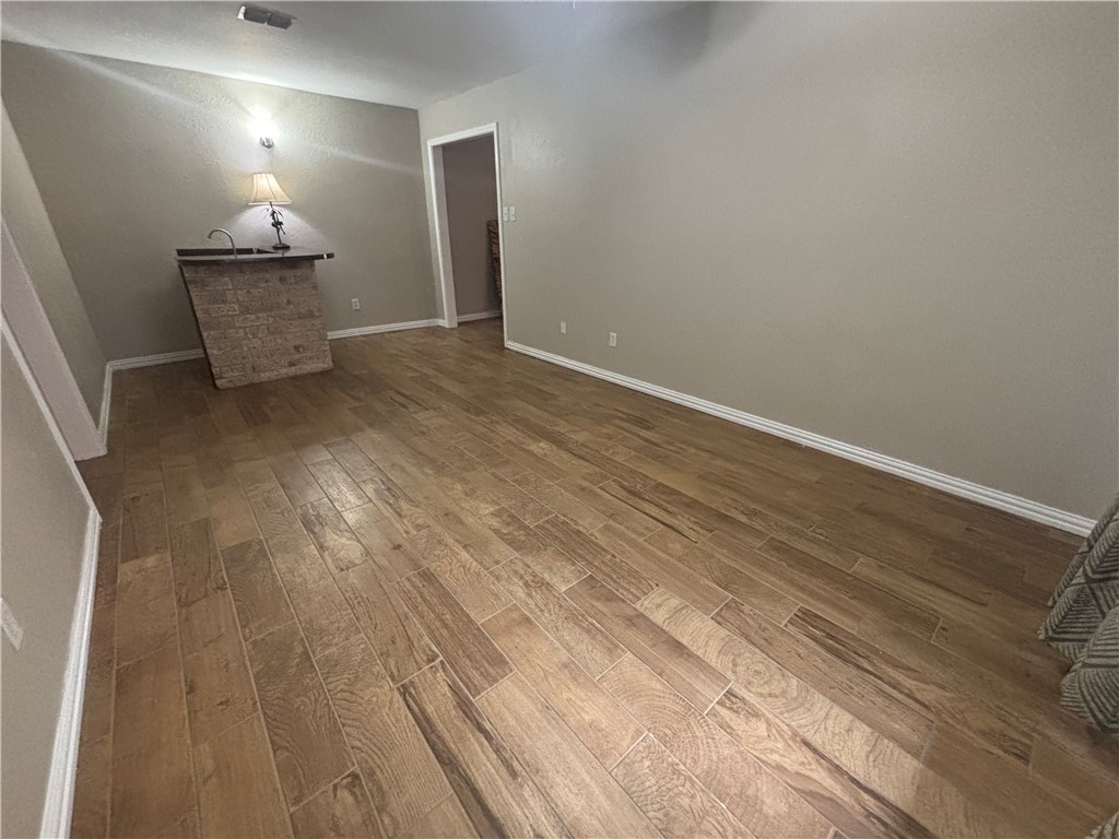 4957 Shadowbend Drive Corpus Christi, TX 78413 - Photo 22 of 35 an empty room with wooden floor windows and exposed bricks
