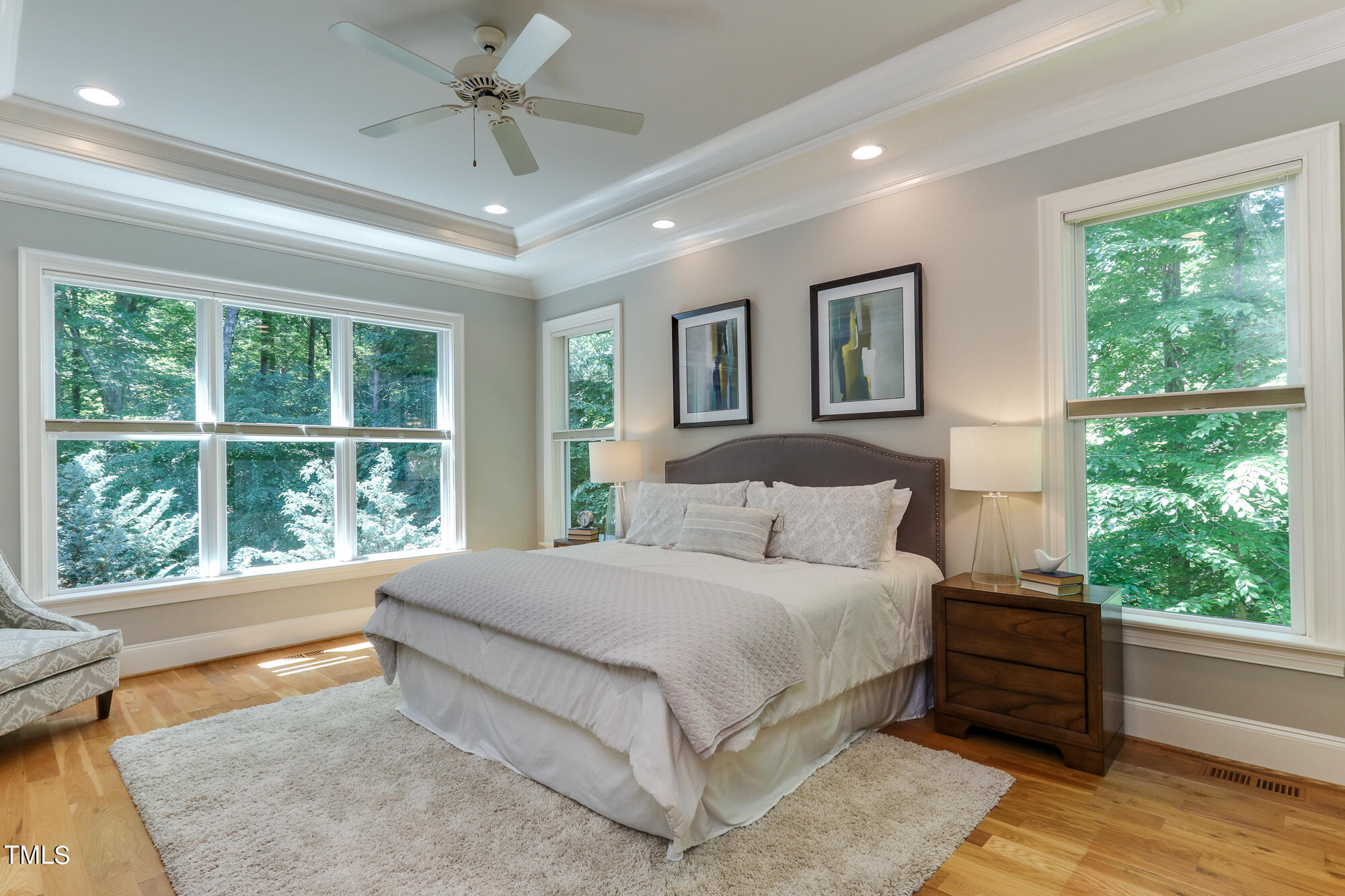 6909 Bartons Bend Way Raleigh, NC 27614 - Photo 14 of 80 Romantic And Tranquil. This Main Floor Primary Bedroom Has The Feel Of Being In A Resort With Gorgeous Natural Views. Imagine The Colors Of Autumn You Will Enjoy From This Suite. Reading Lights and A Tray Ceiling Complete The Room