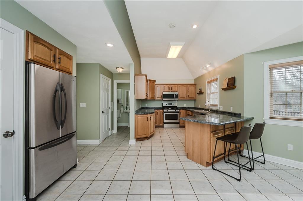 459 Forest Ridge Road Indiana, PA 15701 - Photo 11 of 45 a kitchen with stainless steel appliances granite countertop a stove a refrigerator a sink a dining table and chairs