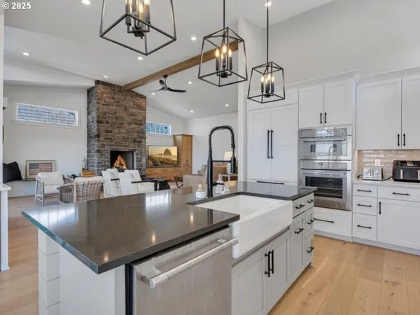 a kitchen with stainless steel appliances granite countertop a sink dishwasher a stove top oven a dining table and chairs with wooden floor