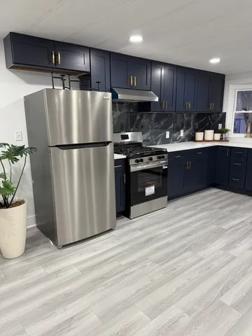 a kitchen with stainless steel appliances granite countertop a refrigerator a stove a sink and a microwave