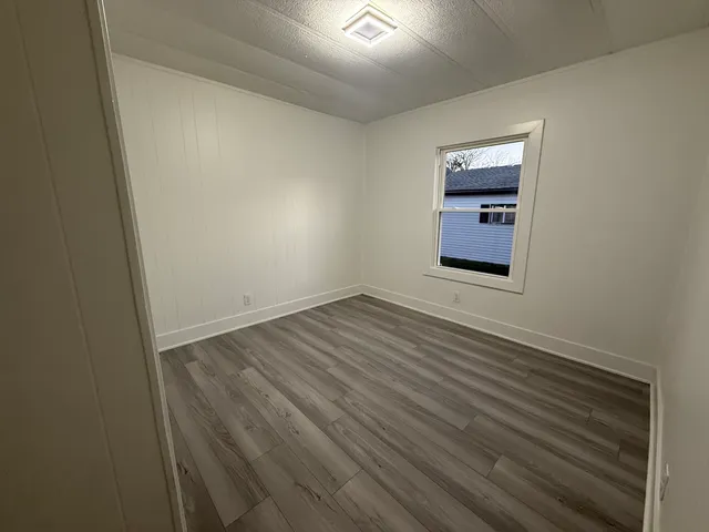 an empty room with wooden floor and window