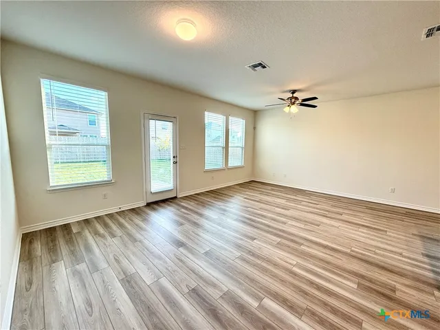an empty room with wooden floor and windows