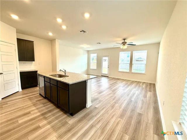a kitchen with stainless steel appliances kitchen island granite countertop a sink and a stove top oven with wooden floor