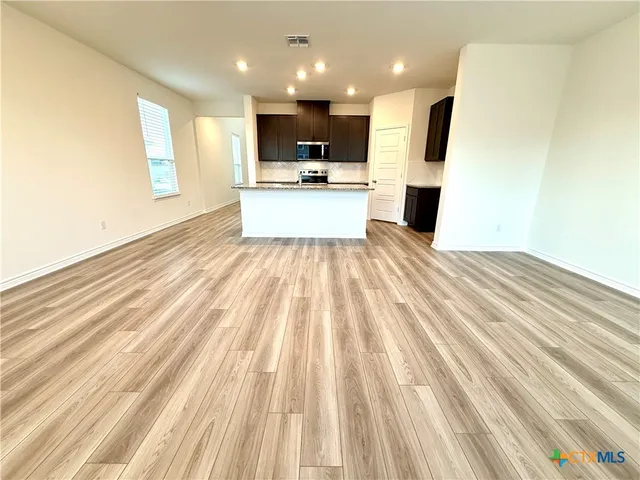 an empty room with kitchen appliances and a ceiling fan