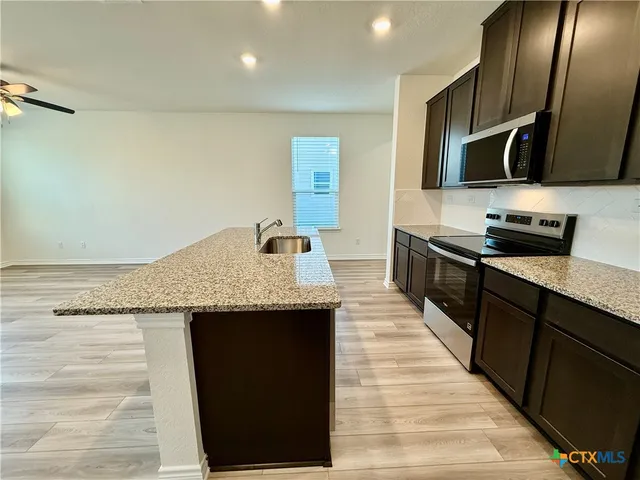 a kitchen with granite countertop a stove and a wooden floor