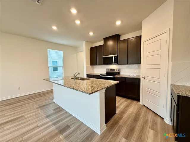 a kitchen with granite countertop a sink a counter top space appliances and cabinets
