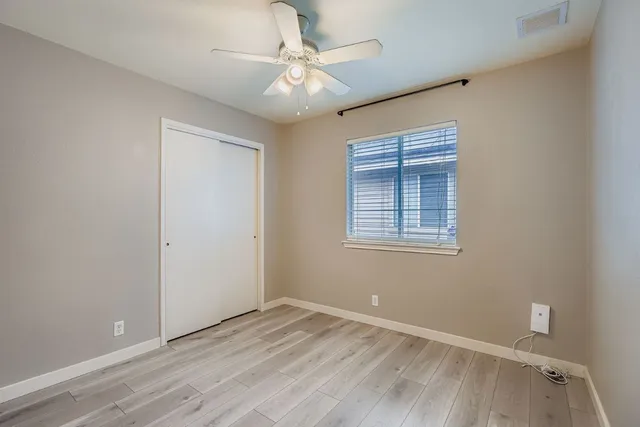 a view of an empty room with window and chandelier fan