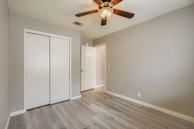 an empty room with wooden floor closet and fan chandelier fan