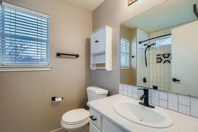 a bathroom with a toilet sink a mirror and shower