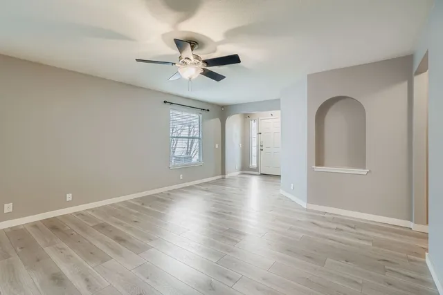 a view of an empty room with wooden floor and a window
