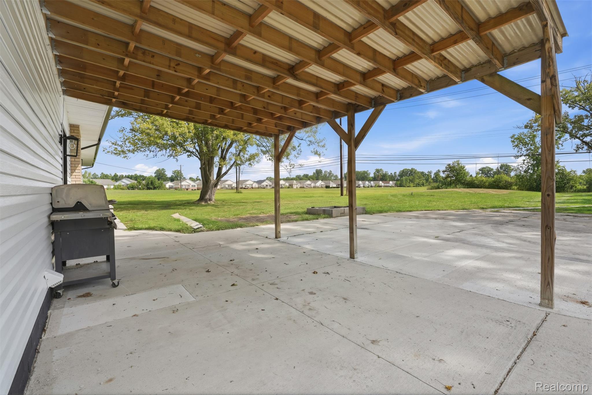 4655 Denton Road Canton, MI 48188 - Photo 36 of 54 Expansive concrete patio with a wood-framed, corrugated metal roof covering
