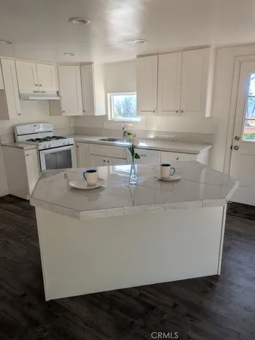 a kitchen with granite countertop white cabinets and white appliances