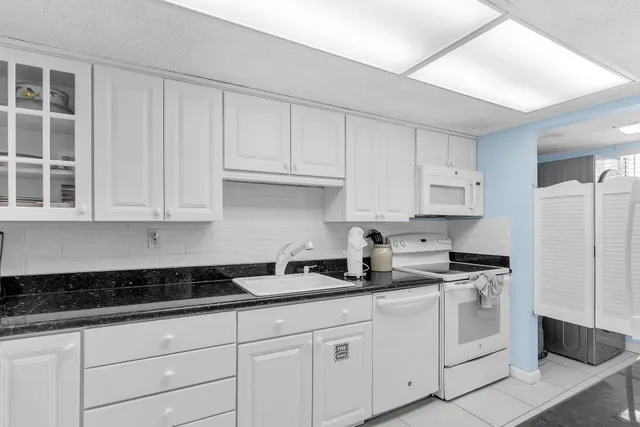 a kitchen with granite countertop a sink a stove and cabinets
