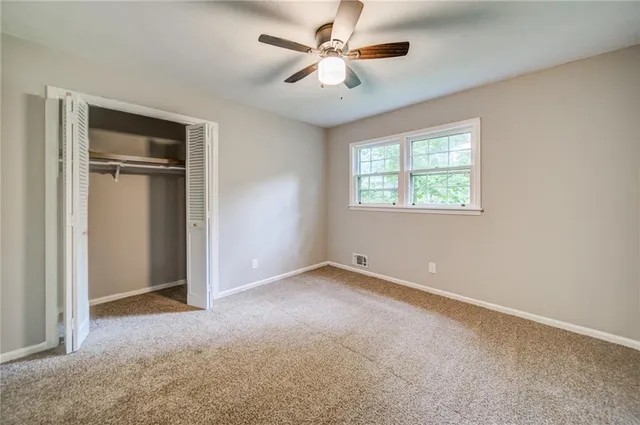 an empty room with closet and a chandelier fan