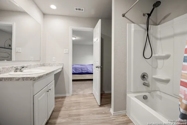 a spacious bathroom with a tub sink and mirror
