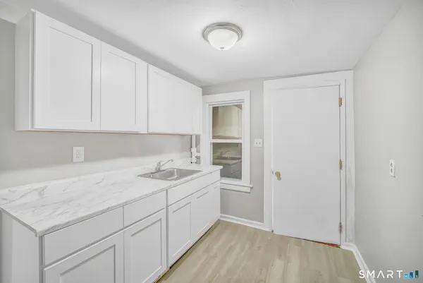 a view of a sink and dishwasher with white cabinets