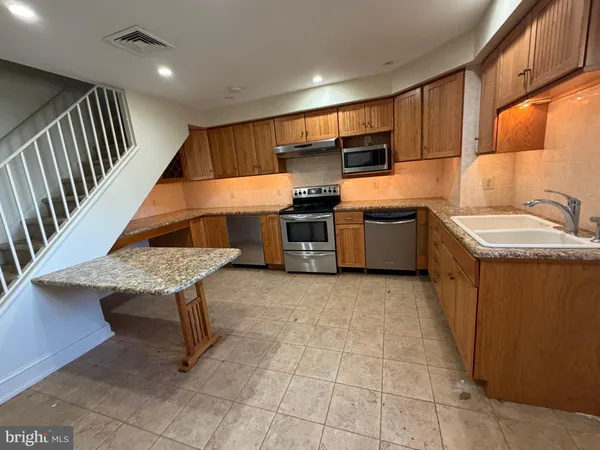 a kitchen with stainless steel appliances kitchen island granite countertop a sink and a refrigerator