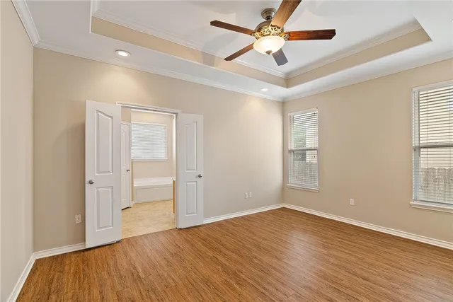 a view of empty room with wooden floor and fan