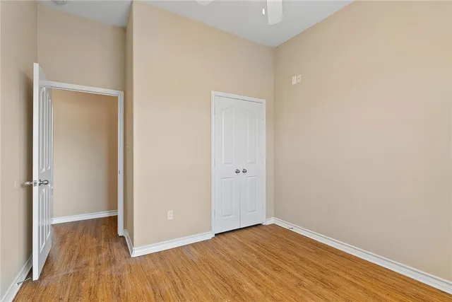 a view of an empty room with wooden floor and closet