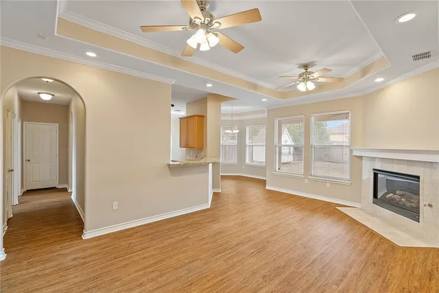 a view of an empty room with wooden floor and a fireplace