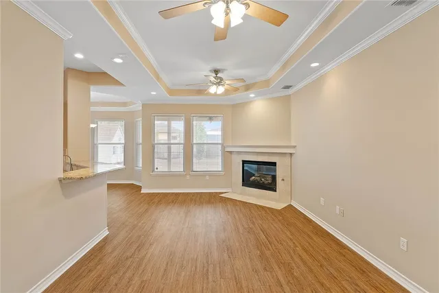 an empty room with wooden floor fireplace and windows