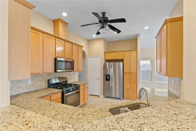 a kitchen with stainless steel appliances granite countertop a sink a stove and a refrigerator