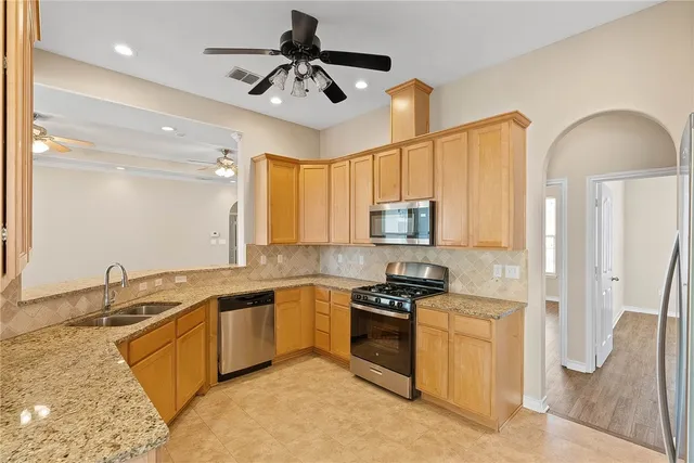 a kitchen with stainless steel appliances granite countertop a sink a stove and a refrigerator