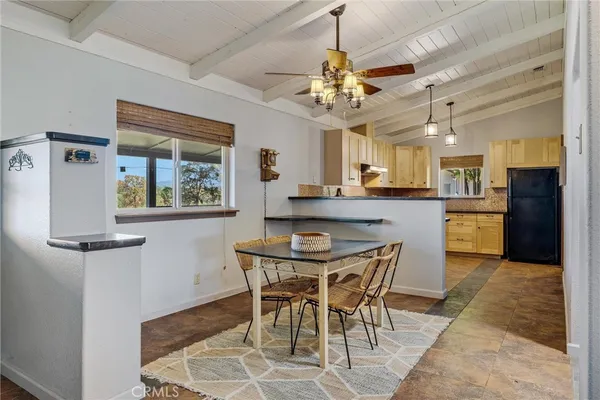 a kitchen with stainless steel appliances granite countertop a refrigerator a sink dishwasher a stove and a dining table with wooden floor