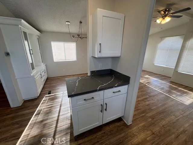 a kitchen with granite countertop a stove and white cabinets