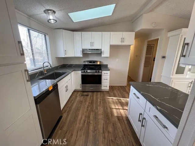 a kitchen with granite countertop a sink stove and refrigerator