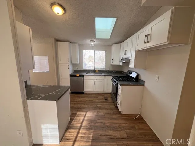 a kitchen with granite countertop a sink a counter space and cabinets