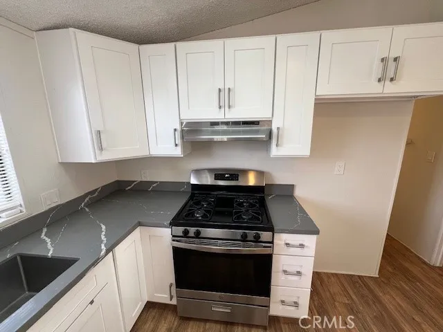 a kitchen with granite countertop white cabinets and black appliances