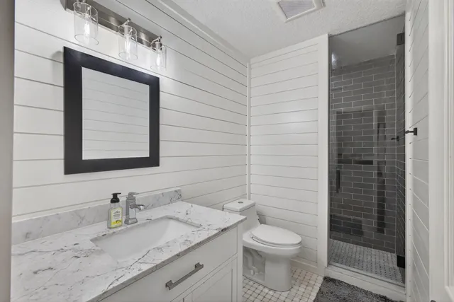 a bathroom with a granite countertop toilet a sink a mirror and shower