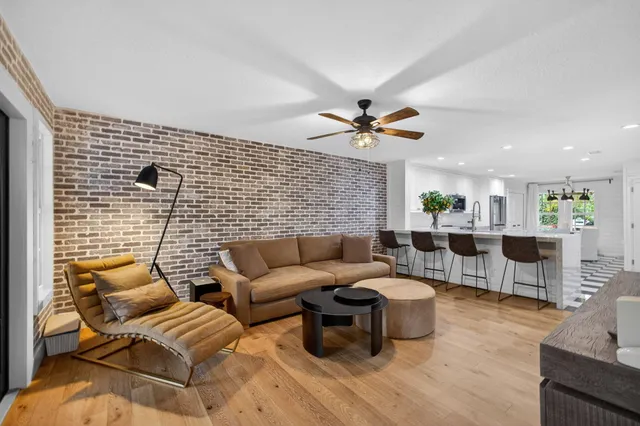 a living room with couches and kitchen view with wooden floor