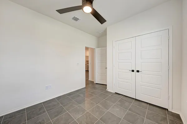 an empty room with a ceiling fan and window