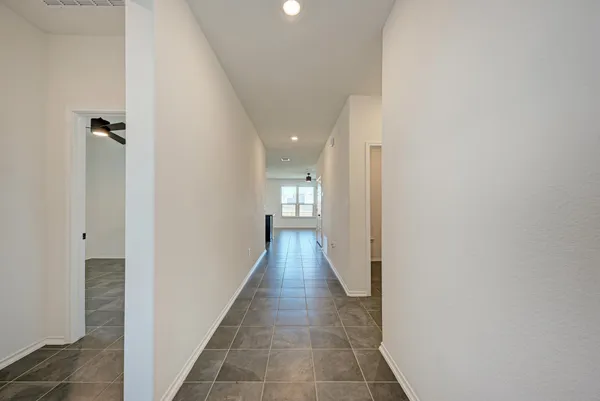 a view of an empty room with a window and a kitchen