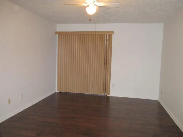 an empty room with wooden floor and fan