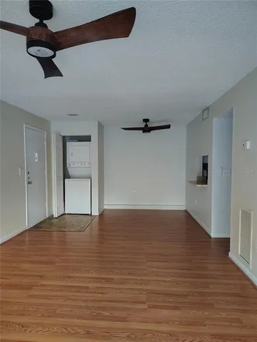 a view of an empty room with a window and wooden floor
