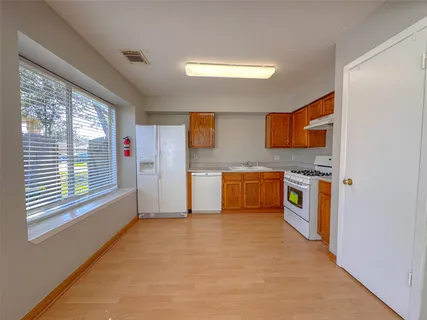 a view of a kitchen with stainless steel appliances granite countertop a refrigerator and a stove top oven