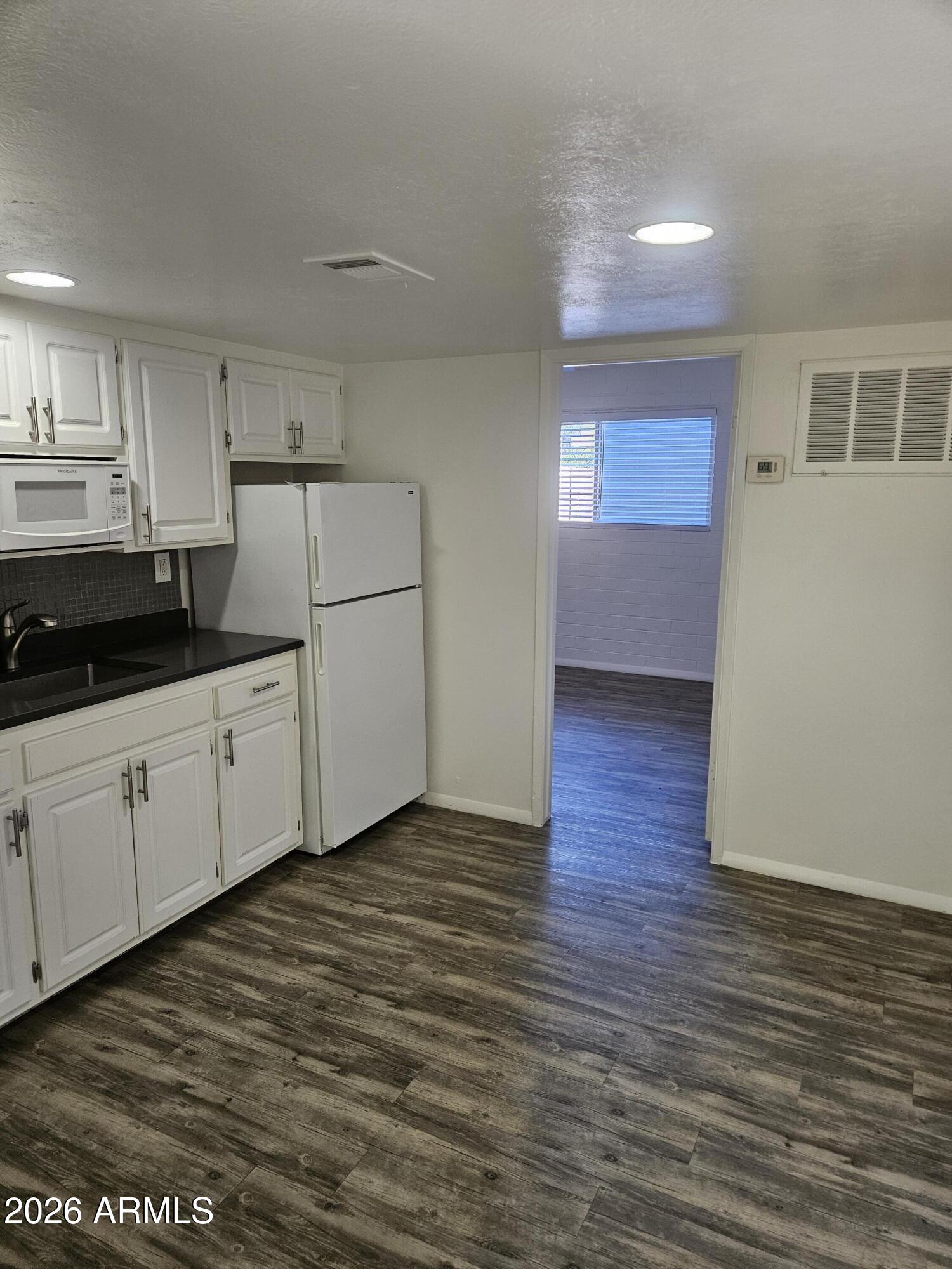 1418 East Osborn Road, Unit 25A Phoenix, AZ 85014 - Photo 4 of 13 a kitchen with granite countertop a stove a refrigerator and white cabinets with wooden floor