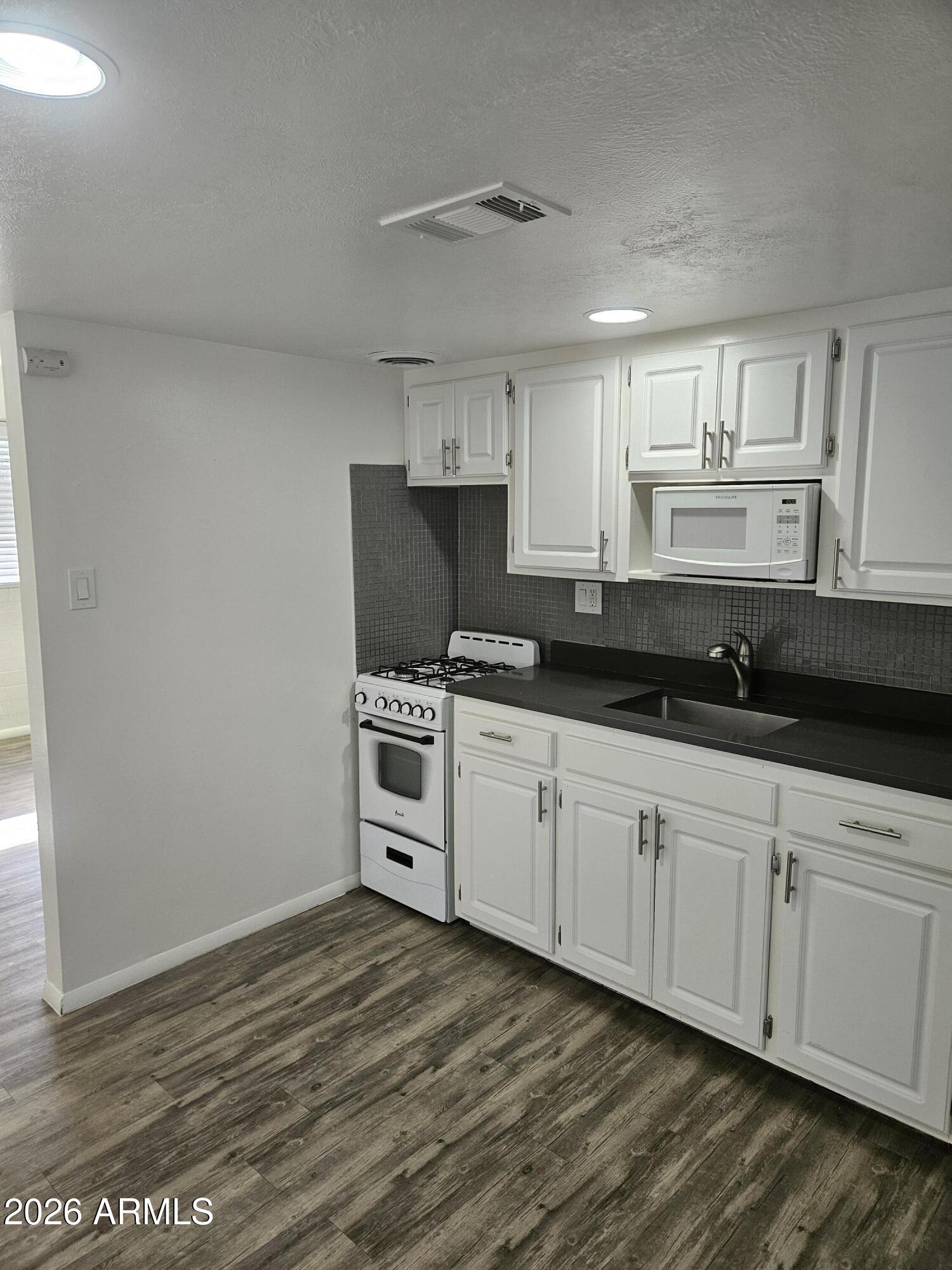 1418 East Osborn Road, Unit 25A Phoenix, AZ 85014 - Photo 5 of 13 a kitchen with granite countertop a stove a sink and a microwave