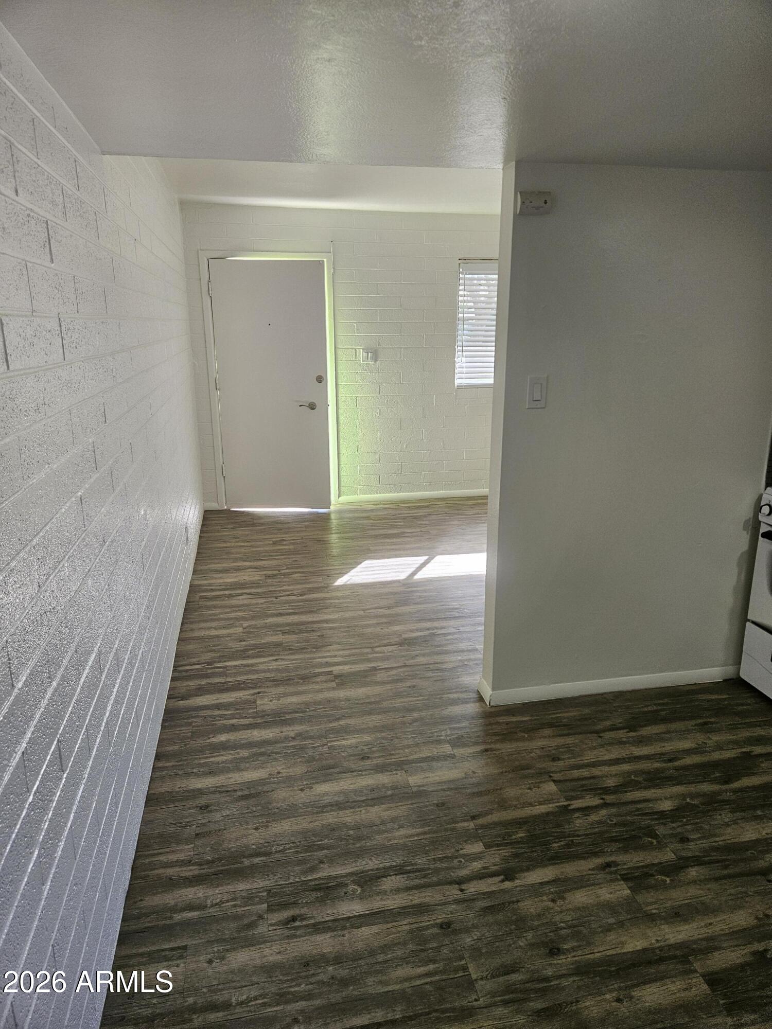 1418 East Osborn Road, Unit 25A Phoenix, AZ 85014 - Photo 6 of 13 a view of an empty room with wooden floor and a window