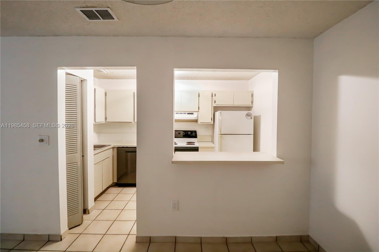 12955 Southwest 66th Lane, Unit 2122 Miami, FL 33183 - Photo 6 of 16 a view of a kitchen with a sink and dishwasher a refrigerator with white cabinets