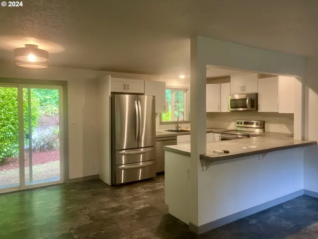 a kitchen with stainless steel appliances granite countertop a refrigerator a stove a sink and a microwave